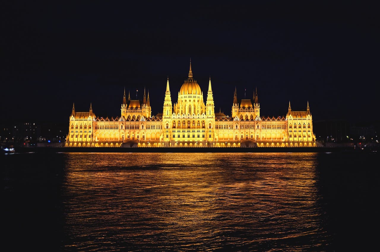 Illuminated Hungarian Parliament Building at night overlooking the Danube River in Budapest.