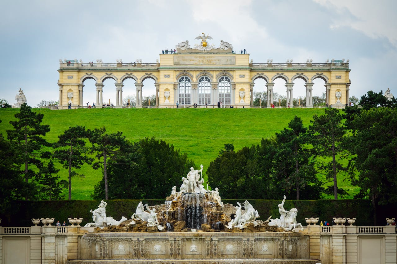 Beautiful view of the Gloriette Schonbrunn in Vienna, Austria, with lush green surroundings and a majestic fountain.