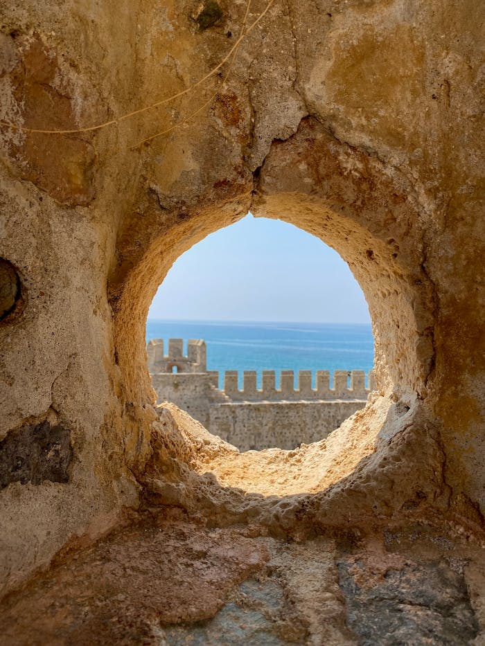 View through a round hole in an ancient wall overlooking a beautiful seascape.