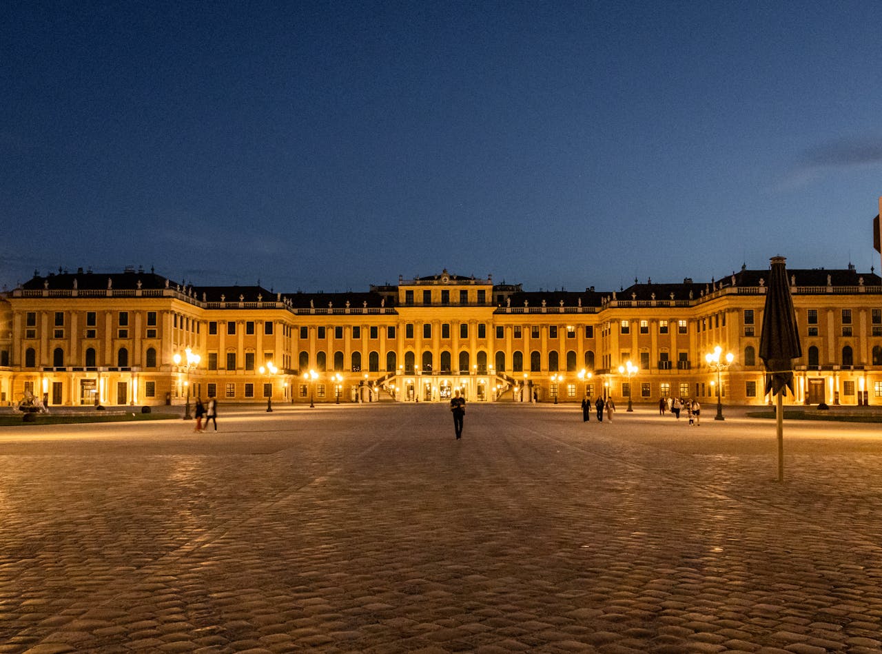 A stunning nighttime view of the beautifully illuminated Schönbrunn Palace in Vienna, Austria.