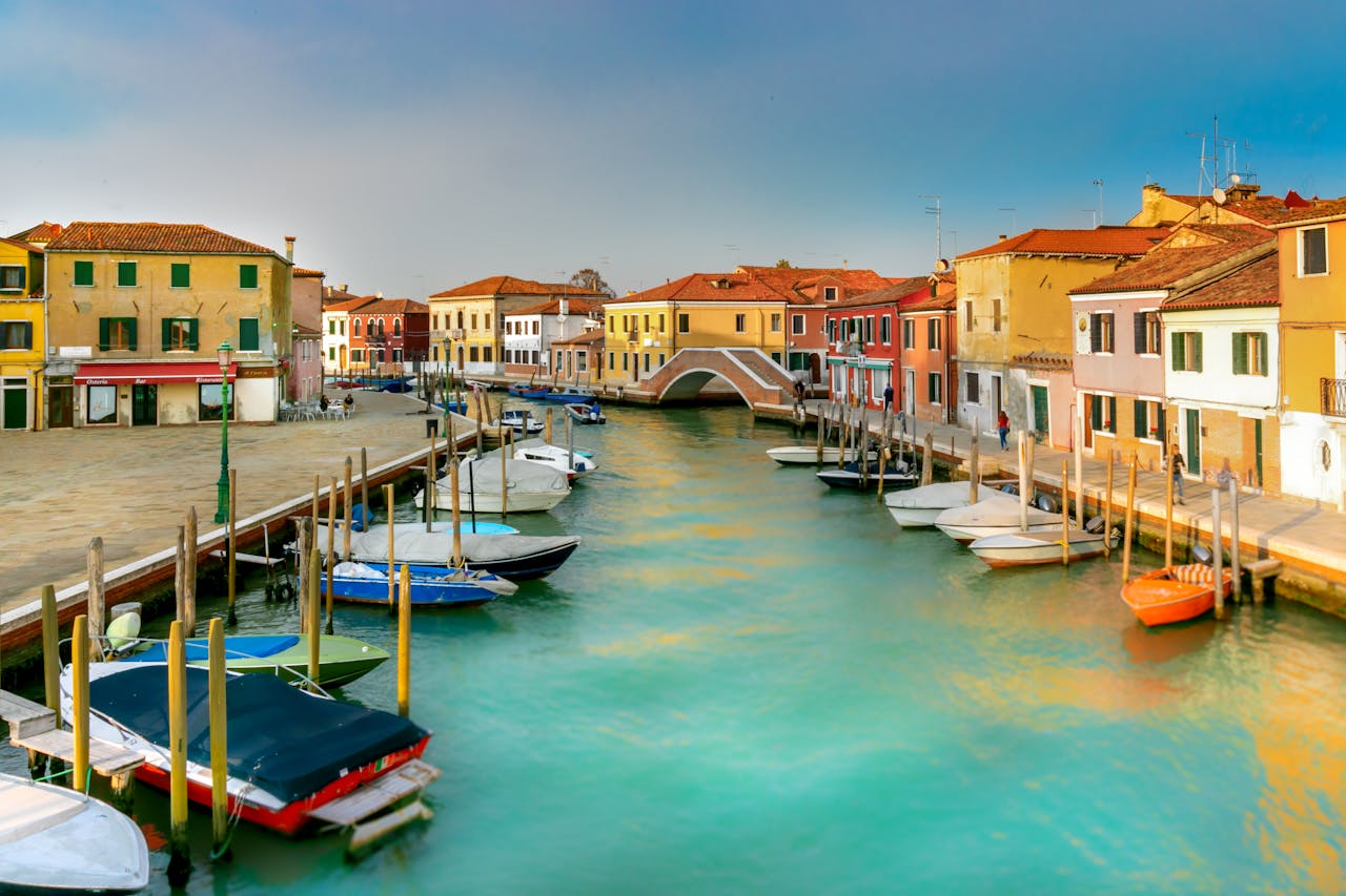 Colorful buildings lined along a serene canal with boats in Murano, Venice.